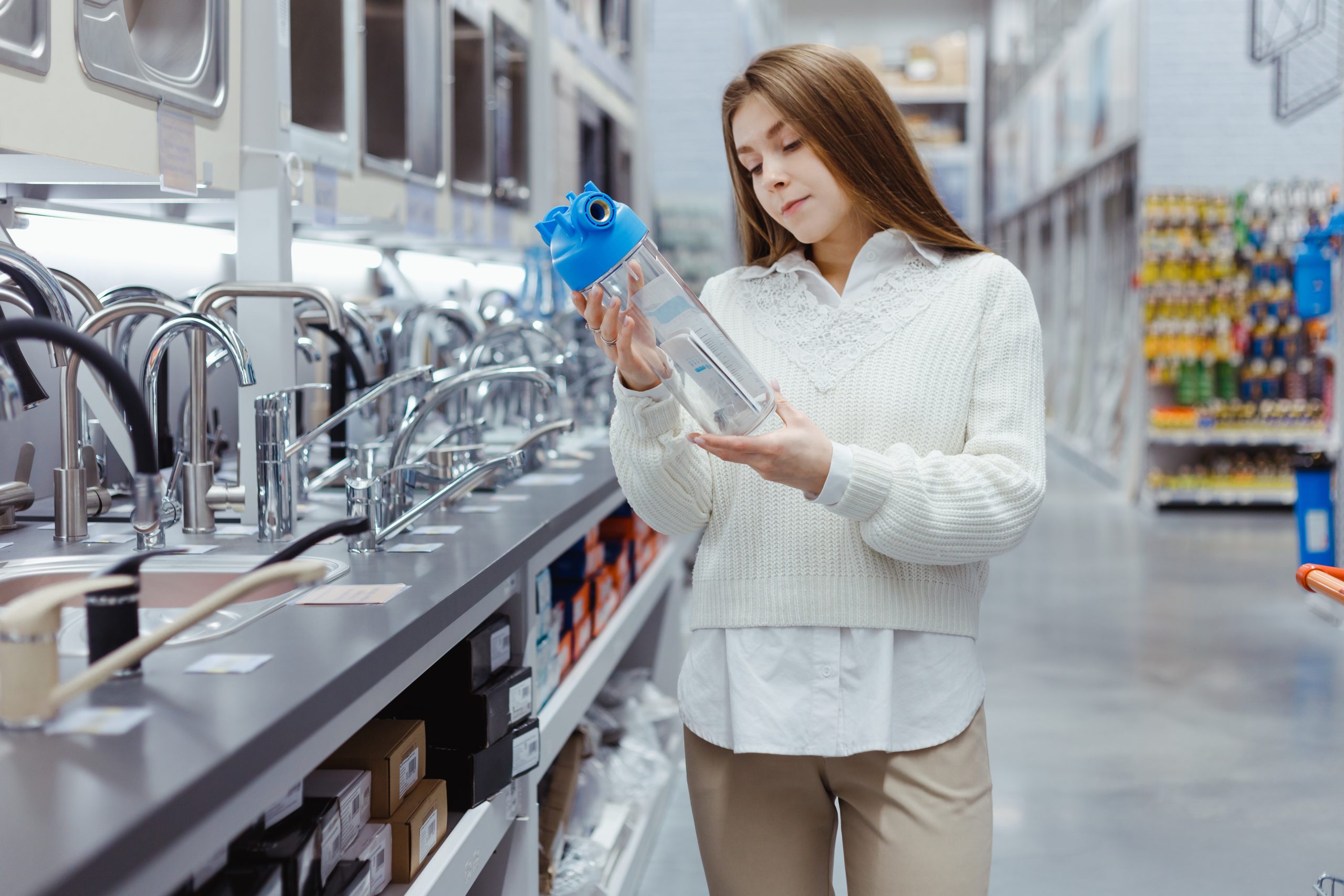 Woman holds household water filter for purification from mechanical impurities in hardware store. Repair of the water supply system at home, purchase of a filter. Woman in plumbing section